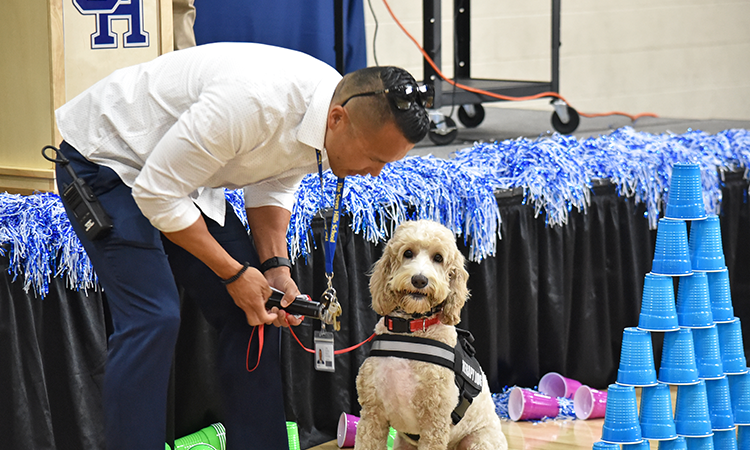 Jun-and-Cruz-during-the-assembly Jun Cho stands with school therapy dog Cruz