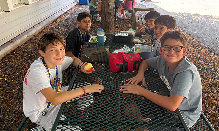 Middle Schoolers eat lunch at a table outside