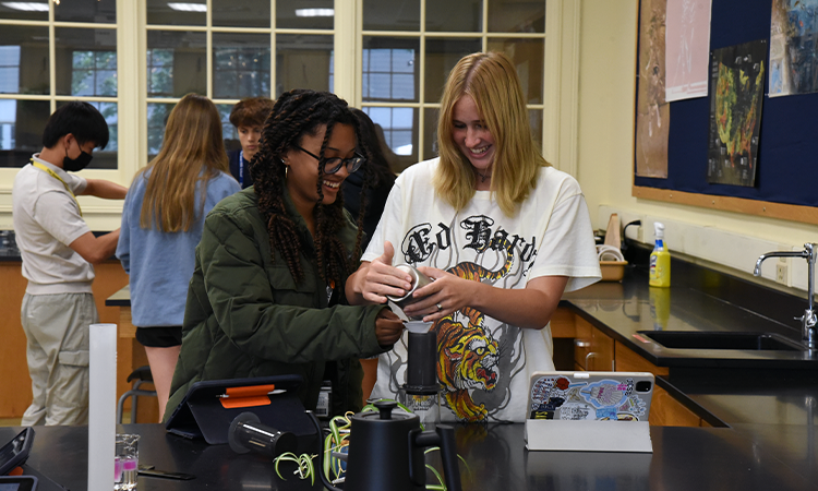 Two students pour out coffee grounds during a coffee extraction lab