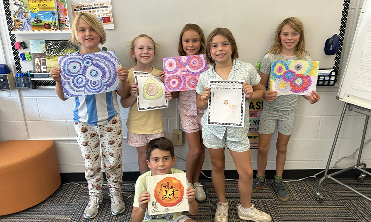 Students hold up their drawings for International Dot Day