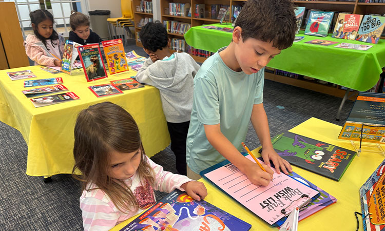 Students-Fill-out-their-Book-Fair-Wishlist A second grader helps a kindergartner fill out their book fair wish list